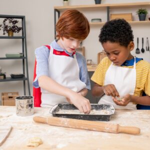 Kids rolling dough while cooking homemade pastry
