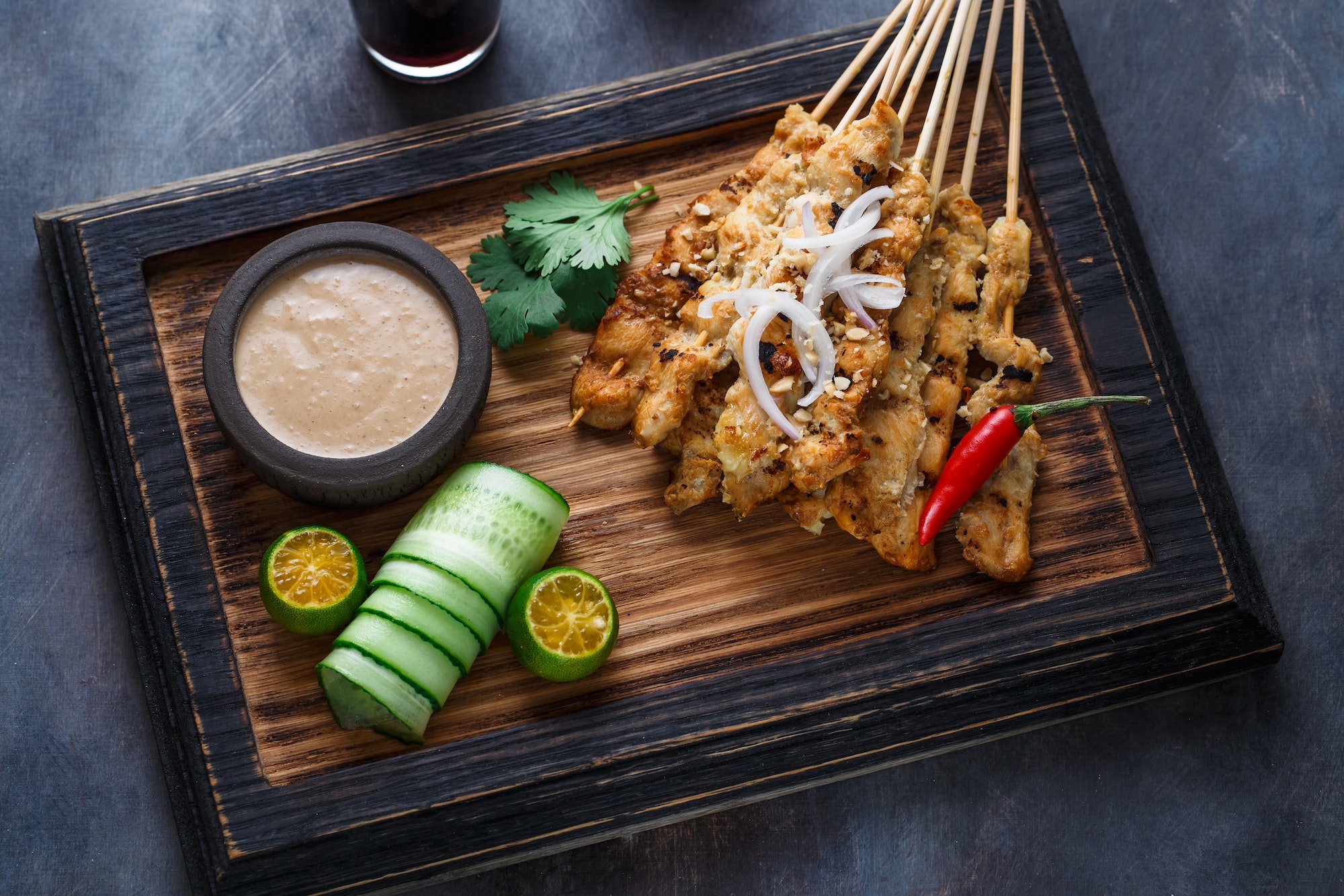 Close view of malaysian chicken skewers - satay or sate ayam with peanut sauce, dark background